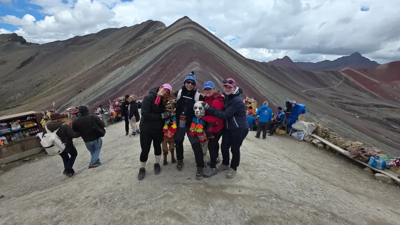 Travelers with decorated alpacas at the Rainbow Mountain viewpoint