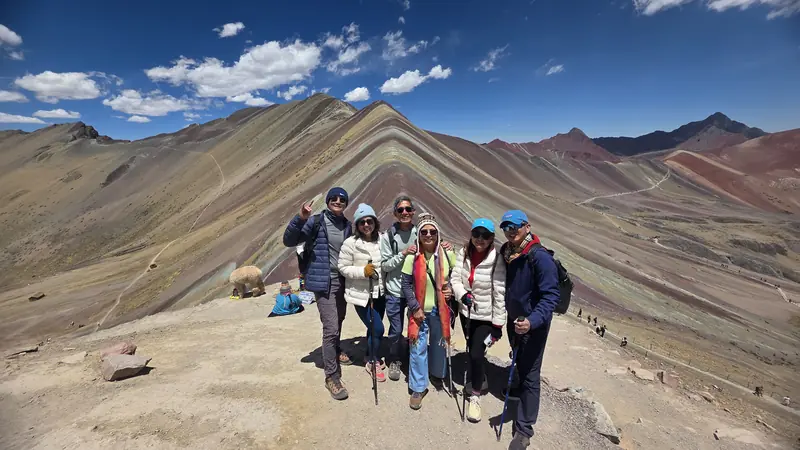 A group of travelers at the Rainbow Mountain summit viewpoint at 5,030 m