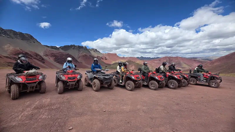 Quad bikes parked in a line with their riders on the high plain below Rainbow Mountain