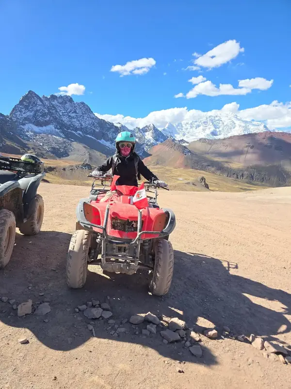 Quad bikes on a dirt road with snow-capped Andean peaks on the horizon